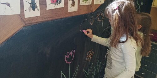 dziewczynka rysuje kredą po tablicy