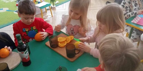 Dzieci przy stoliku kroją pomarańcze