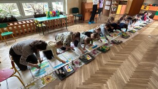dzieci malują farbami na długim kartonie na podłodze