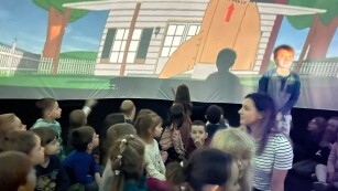 dzieci siedzą w kopule i oglądaja film