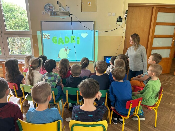 dzieci oglądaja edukacyjny filmik na tablicy multimedialnej