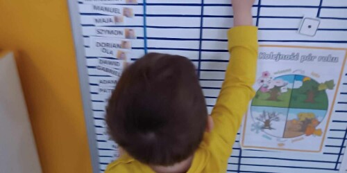 Chłopiec przyczepia magnes do tablicy