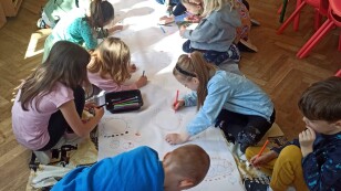 Dzieci malują na kartonie na podłodze