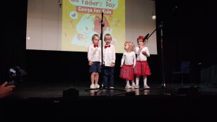 Dzieci stoją na scenie śpiewając piosenkę
