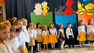 Dzieci w żóltych strojach stoją na scenie